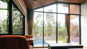 Una habitación moderna con ventanas amplias, techo de madera y vistas a un jardín.