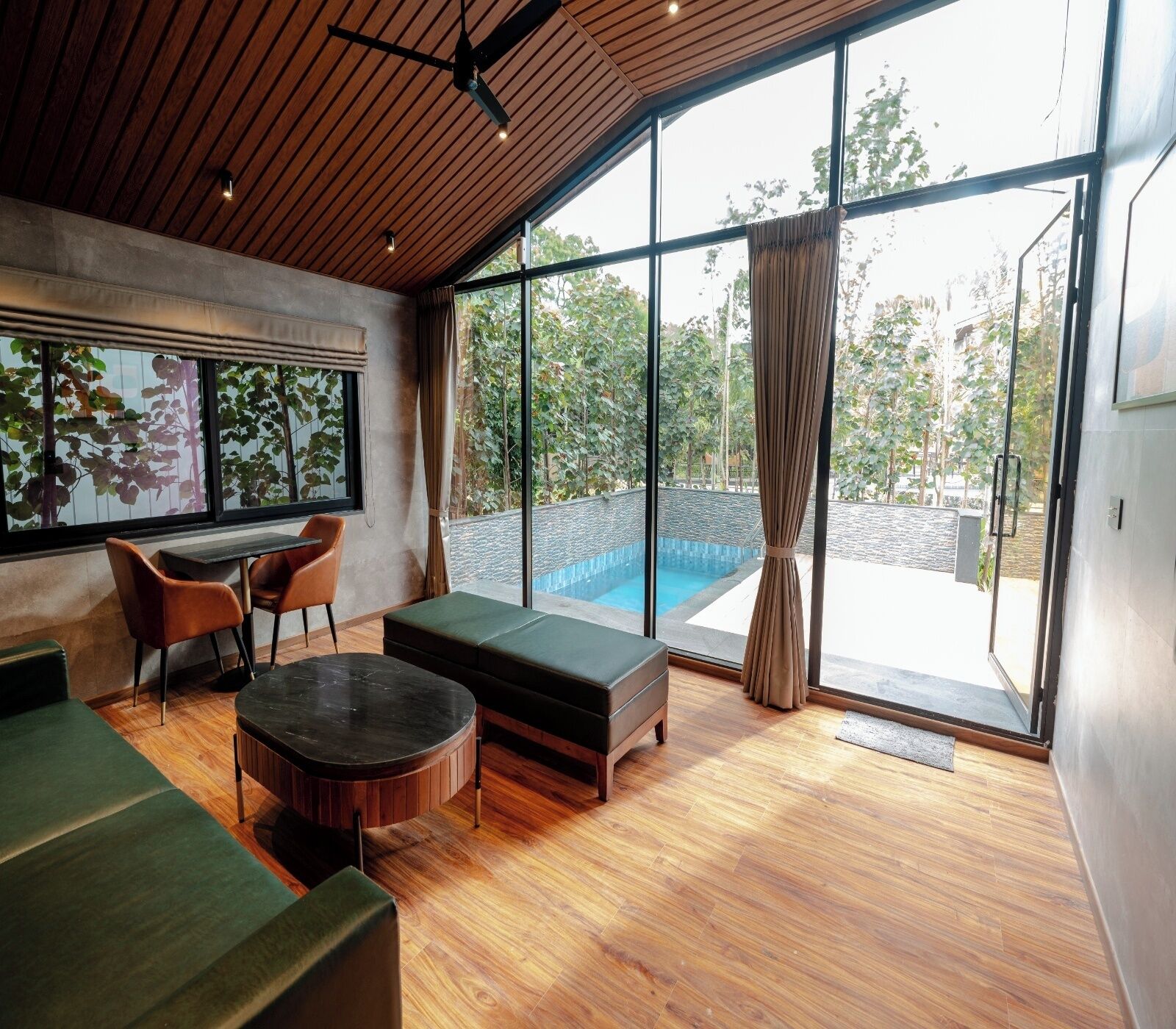 A modern interior with a wooden ceiling, large windows, a pool, and a seating area.
