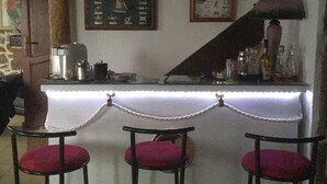 Una zona de bar con mostrador blanco, tres taburetes rojos acolchados y un mapa náutico enmarcado en la pared.