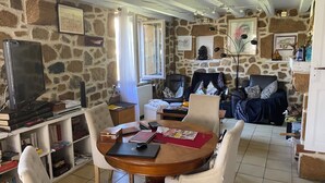 Una sala acogedora con una pared de piedra, una mesa de madera y asientos cómodos.