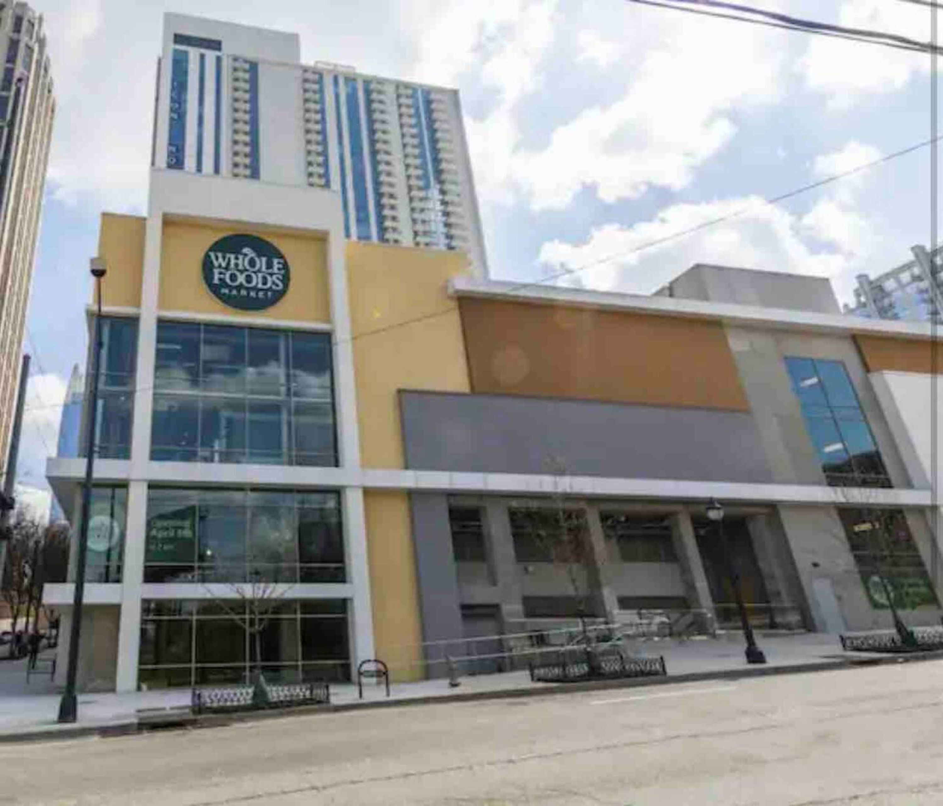 Un magasin Whole Foods Market doté d’une façade moderne en verre et d’une palette de couleurs jaune et blanche.