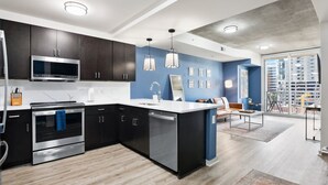 A modern kitchen with dark cabinets, stainless steel appliances, and a large island. - Luxury City Center Home (Atlanta)