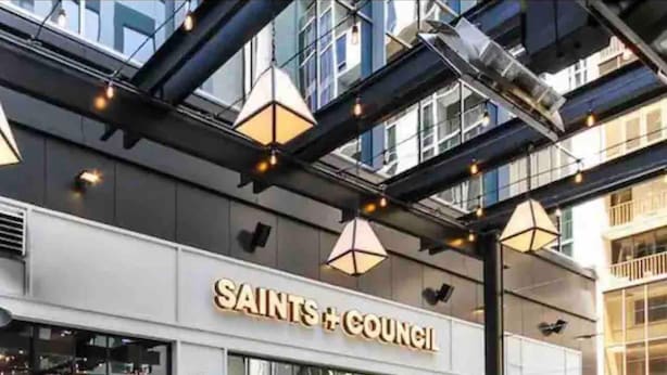 An outdoor seating area with a fire feature, a building with 'SAINTS + COUNCIL' signage, and a modern architectural design. - Luxury City Center Home (Atlanta)
