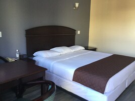 Quarto de hotel com uma cama, uma escrivaninha e uma cadeira.