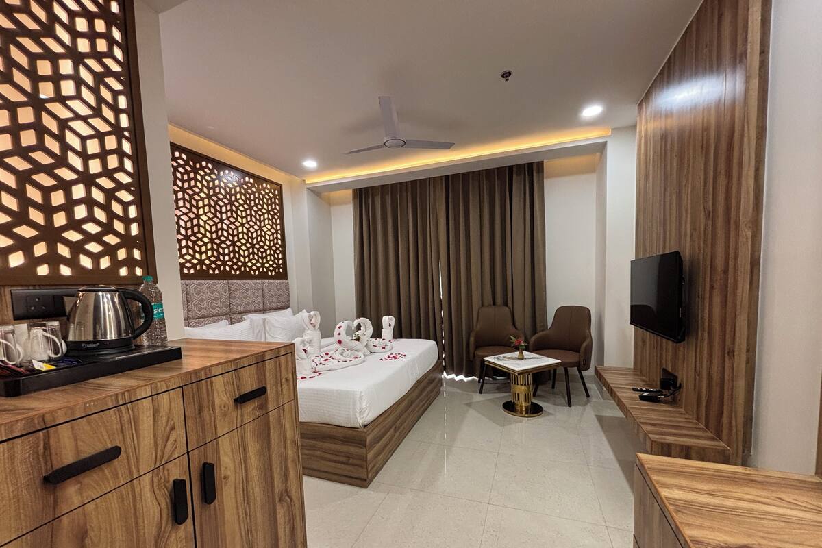 Quarto de hotel moderno com cama, escrivaninha, televisão e área de estar.