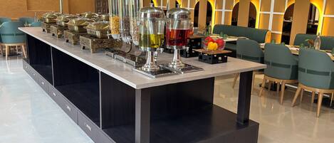 Een buffetopstelling met verschillende voedselcontainers en een drankdispenser.