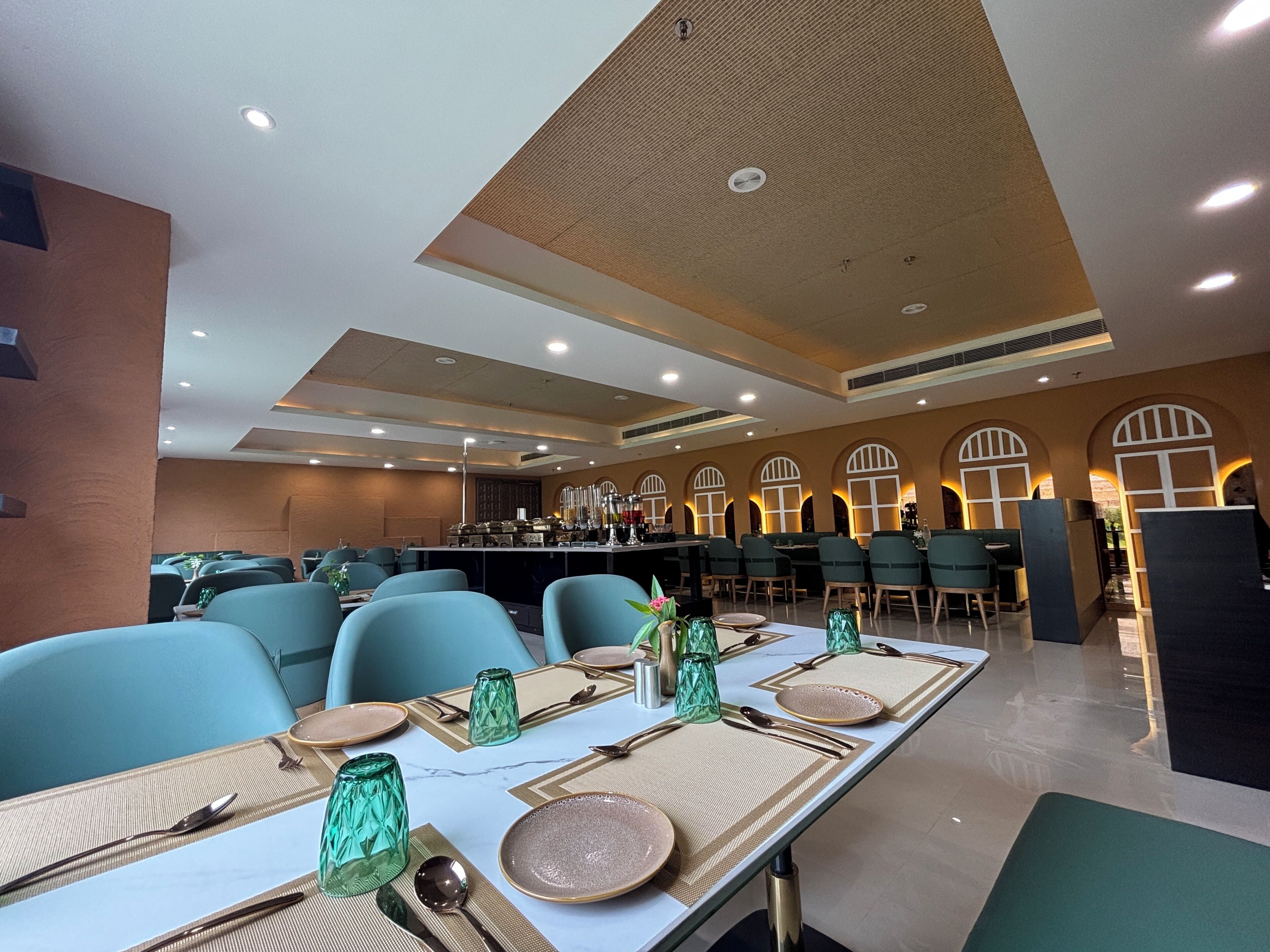 A modern dining area with a long table set for a meal, surrounded by chairs.
