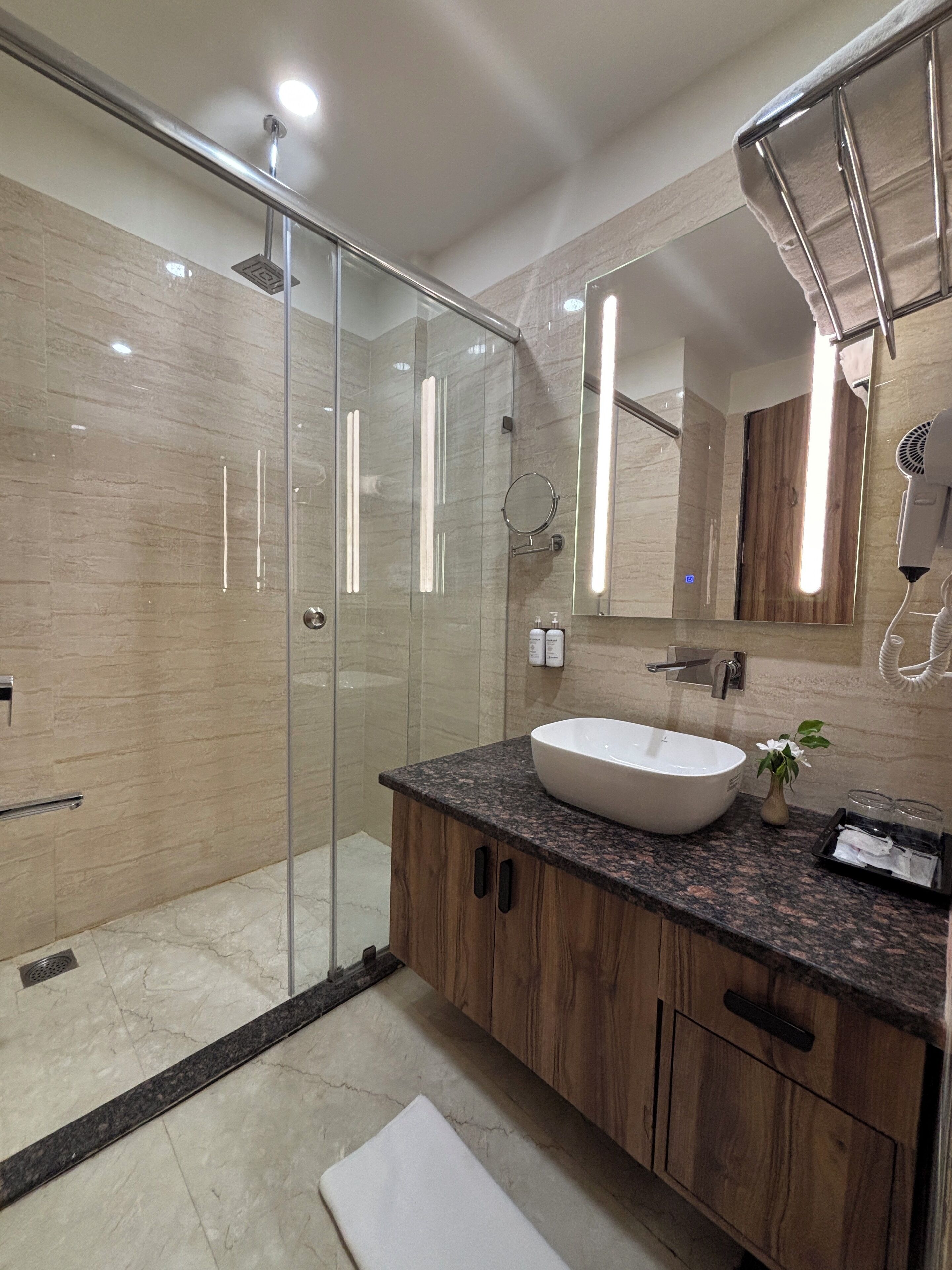 Un baño moderno con ducha de vidrio, un lavabo grande y armarios de madera.