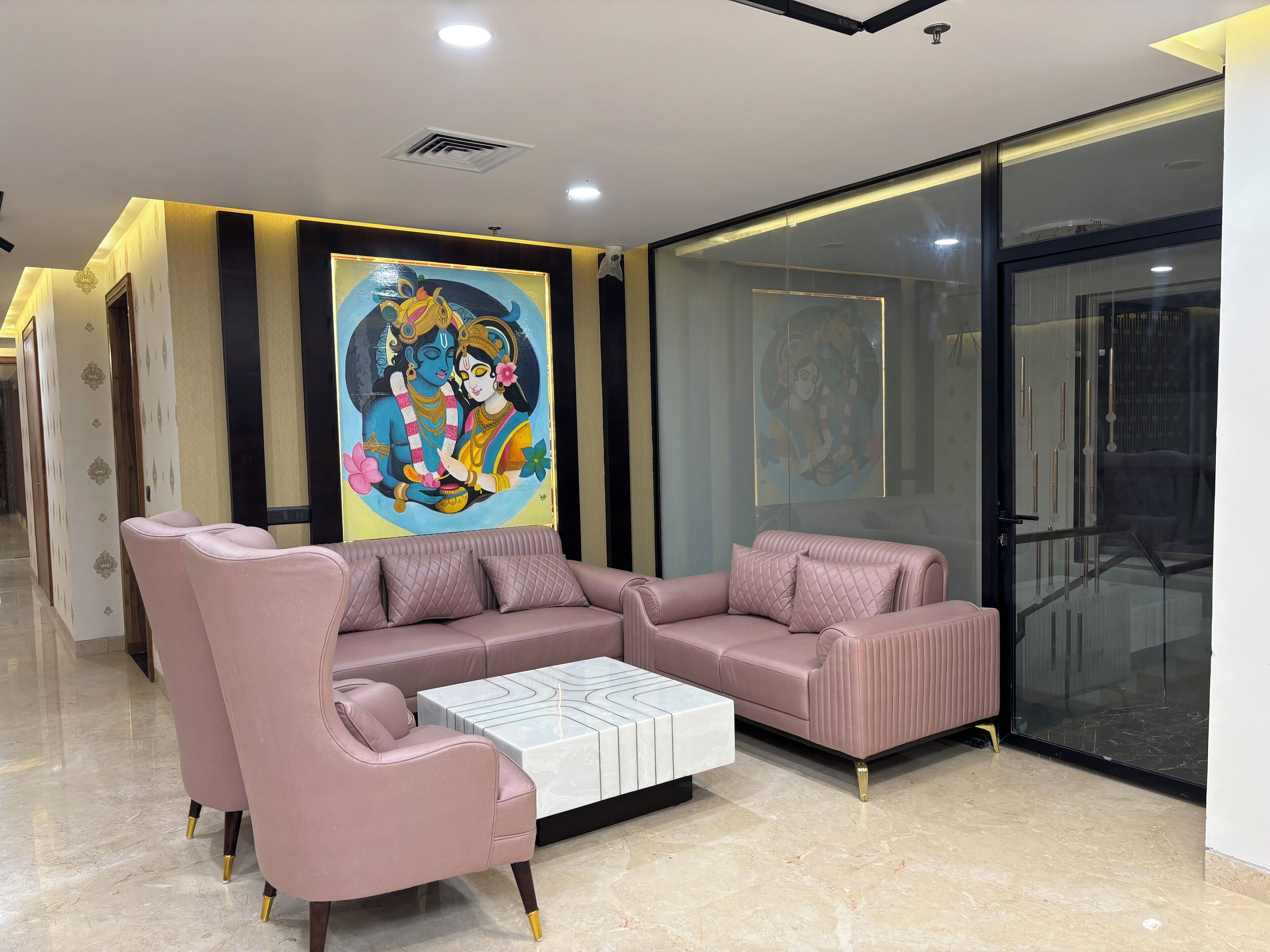 Una sala de estar moderna con un juego de sofá rosa, una mesa de centro blanca y un cuadro religioso grande en la pared.