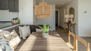 A modern living room with a wooden dining table, a sofa, and a large plant.