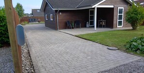 A residential driveway leading to a house with a garage, a paved walkway, and a grassy lawn.
