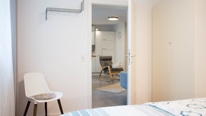 Une chambre à coucher comprenant un lit, une chaise, une armoire et une porte ouverte donnant sur une salle de bain.