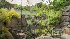 Une terrasse avec des meubles d’extérieur, une table et une chaise, le tout installé sous une pergola.