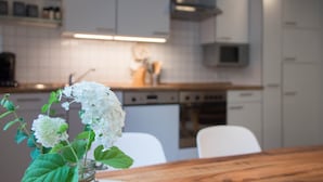 Une cuisine moderne avec des meubles blancs, un plan de travail en bois et un vase rempli de fleurs blanches.