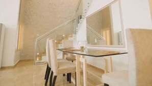 A modern dining area with a glass table and chairs, a staircase, and a large mirror. - Luxurious 4-Bedroom Serviced Penthouse – The Pearls, Ikoyi (Lagos)