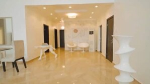 A spacious hallway with a polished floor, a reception desk, and a decorative white column. - Luxurious 4-Bedroom Serviced Penthouse – The Pearls, Ikoyi (Lagos)