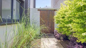 Een modern gebouw met een groot raam, een houten deur en een tuin met diverse planten.