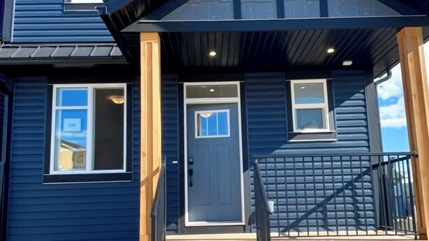 A two-story house with a front porch, a staircase, and a garage door. - Beautiful Cozy Spacious Suite (Calgary)