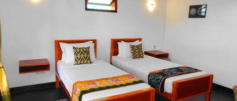 A hotel room with two wooden beds, white bedding, and a small bedside table with a phone.