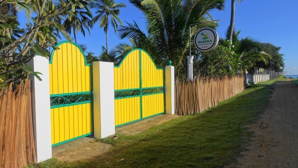 Une propriétéClose, délimitée par une clôture jaune et verte, avec des palmiers et un ciel dégagé.