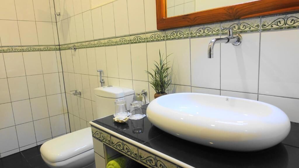 A bathroom with a white toilet, a white sink with a black countertop, and a mirror above the sink.