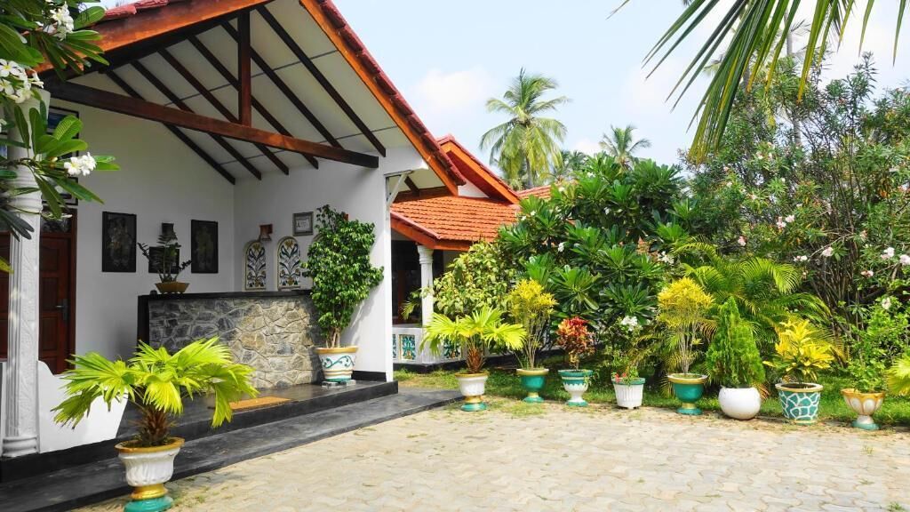 A courtyard with a stone pathway, potted plants, and a building with a tiled roof.