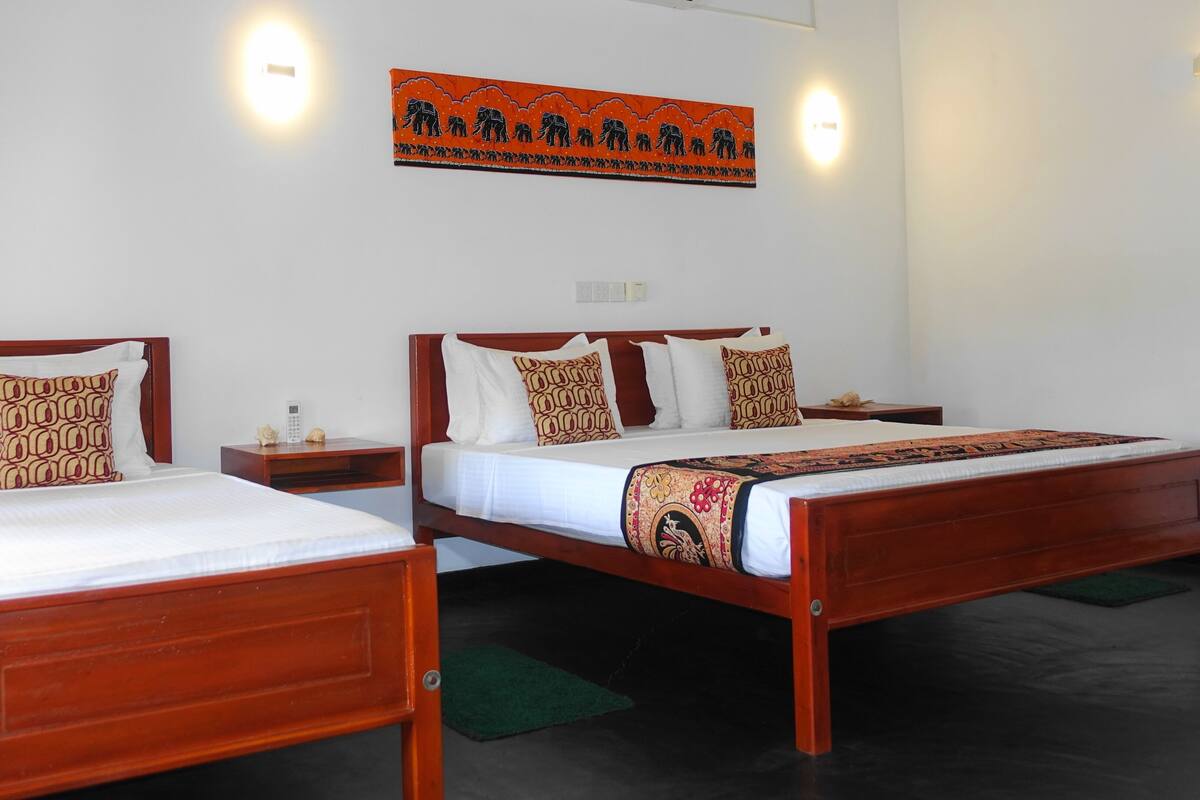A hotel room with two wooden beds, white bedding, and a decorative wall hanging above the beds.