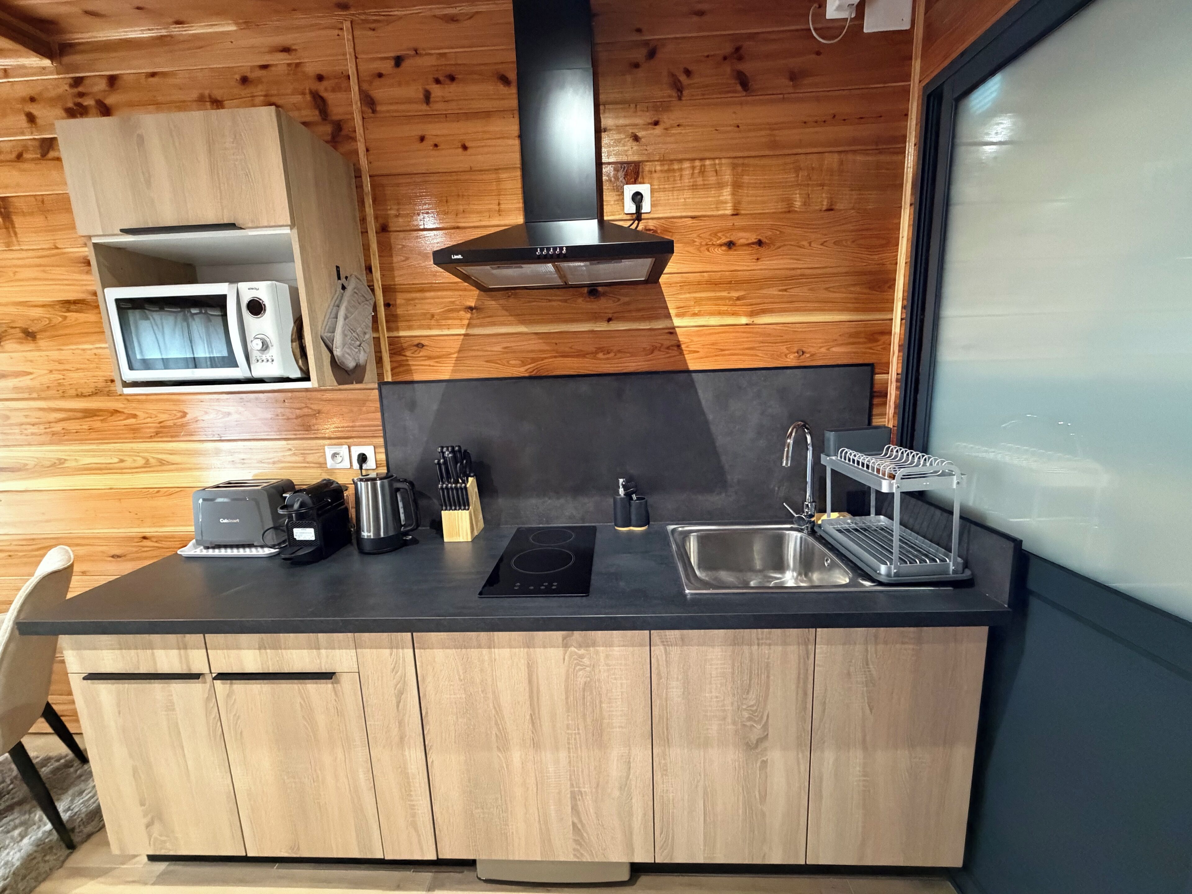 Una cocina compacta equipada con microondas, tostadora, hervidor y pileta.