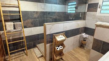 A bathroom with a wooden ceiling, a bamboo ladder, a wall-mounted toilet paper holder, and a bathtub.