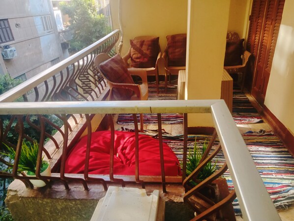 A staircase with a red bean bag chair, wooden chairs, and a colorful woven mat.