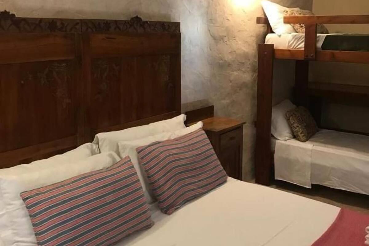 Quarto com cama beliche, cabeceira de madeira, mesa de cabeceira e criado-mudo.