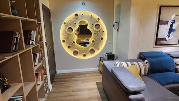 A living room with a circular wall decoration, a sofa, and a bookshelf. - 🏡 Luxury 2 bedroom apartment (Lagos)