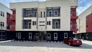 A multi-story residential building with a central entrance, balconies, and a paved courtyard. - 🏡 Luxury 2 bedroom apartment (Lagos)