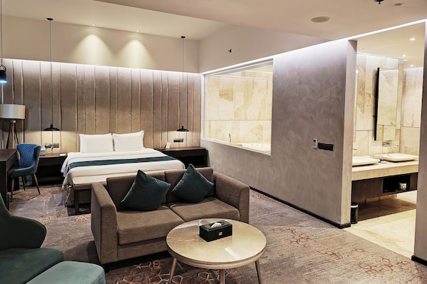 Een moderne hotelkamer met een bed, een bank en een klein tafeltje.