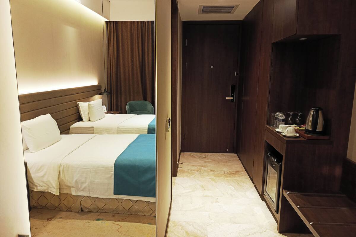 A hotel room with two beds, a desk with a chair, a TV, and a coffee maker.