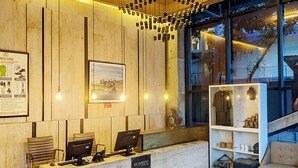 A reception desk with computers, a wooden wall, a framed picture, and a window with a view.