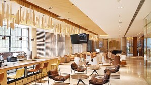 A modern lounge area with a long bar, comfortable seating, and a large flat-screen TV.
