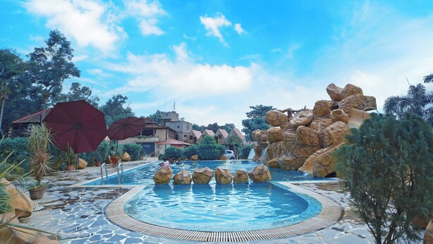 Un área de piscina con una fuente circular de agua, rodeada de rocas y plantas en macetas.