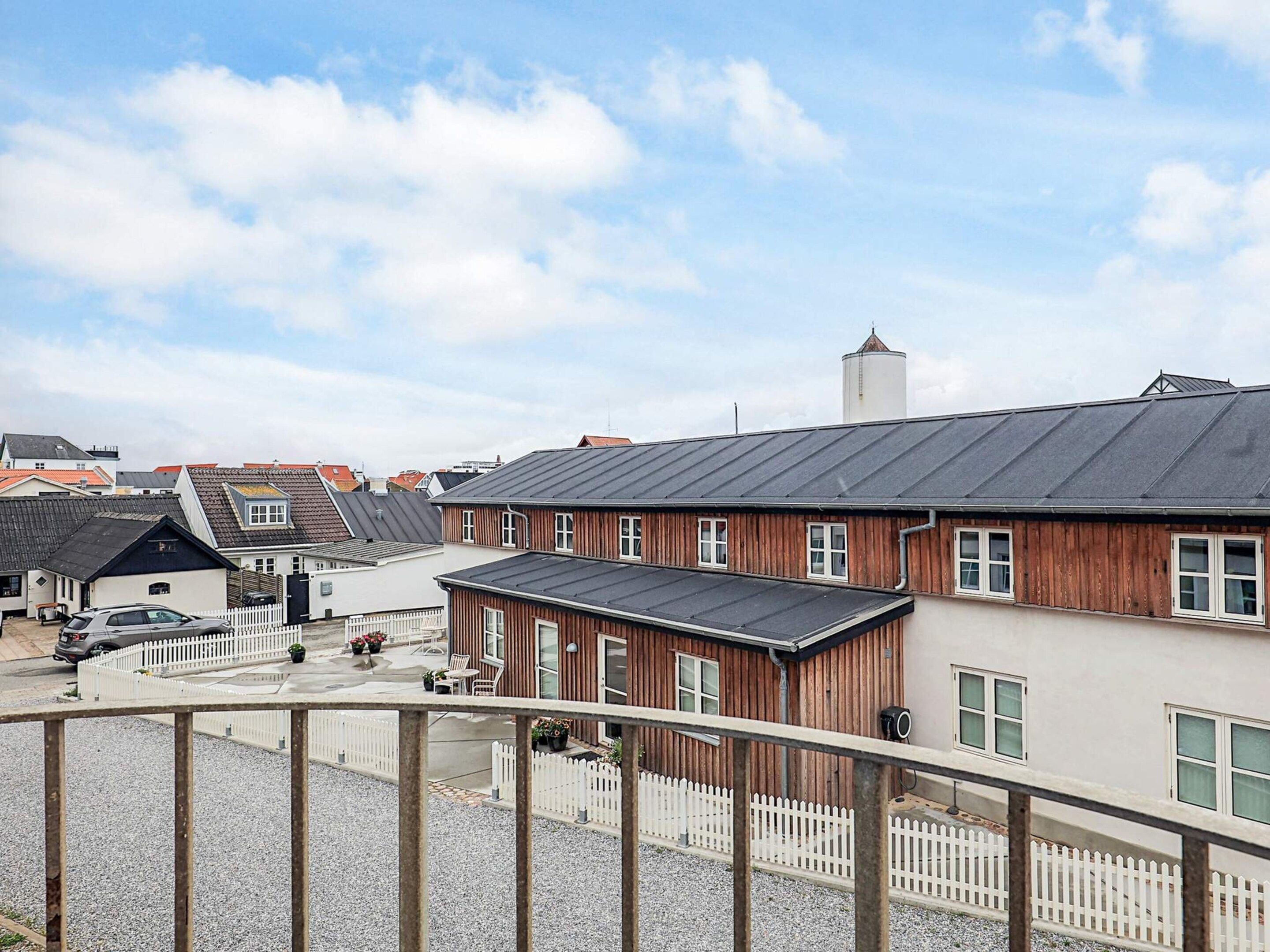 Ein Wohngebiet mit einem Haus, das ein Satteldach, eine Holzfassade und einen weißen Zaun hat.