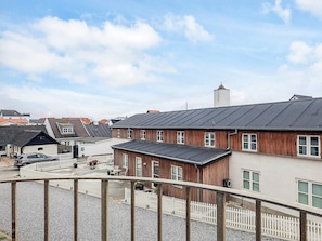 A residential area with a house featuring a sloped roof, a wooden exterior, and a white picket fence. - 5 Star Holiday Home in Lokken (Lokken)