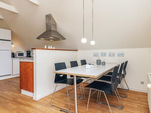 A modern kitchen with a central island, a dining area with a large table and chairs, and a visible ceiling vent. - 5 Star Holiday Home in Lokken (Lokken)