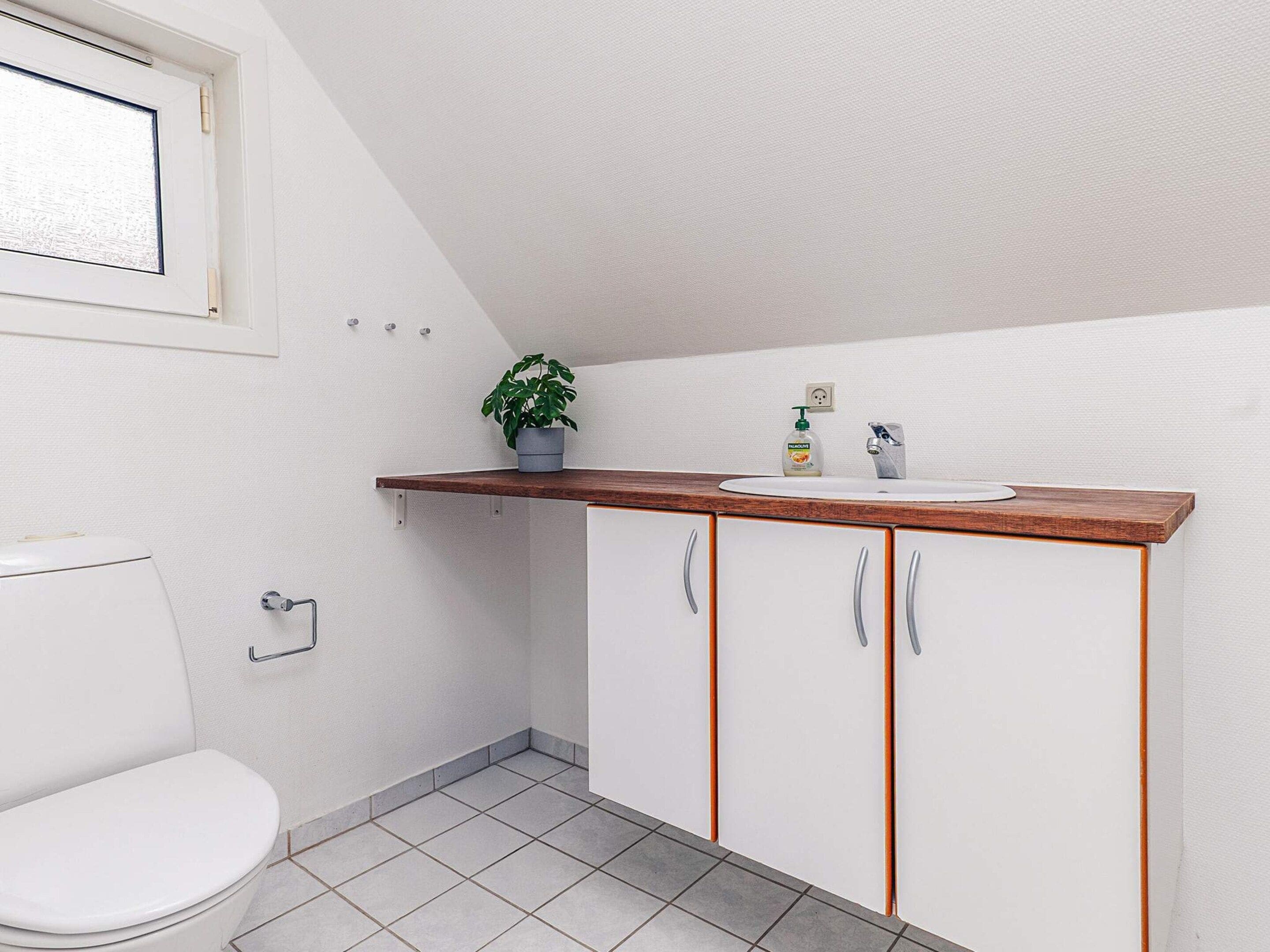 A small bathroom with a toilet, a sink, and cabinets.