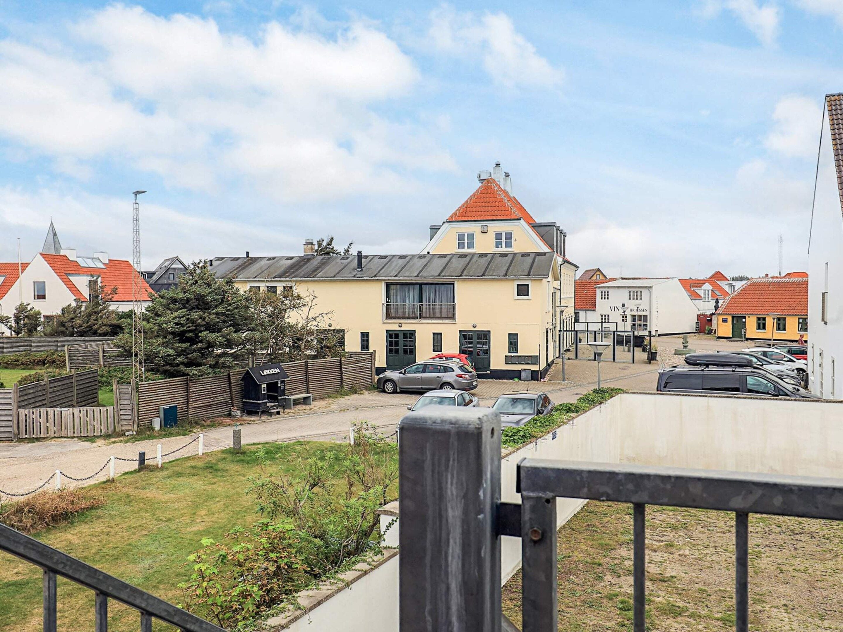 A residential area with a two-story house, a parked car, and a small fenced garden.