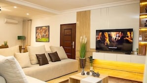 A modern living room with a sofa, a TV, and a small coffee table. - Smart 3-Bedroom Apartments – A Home Away From Home (Lagos)