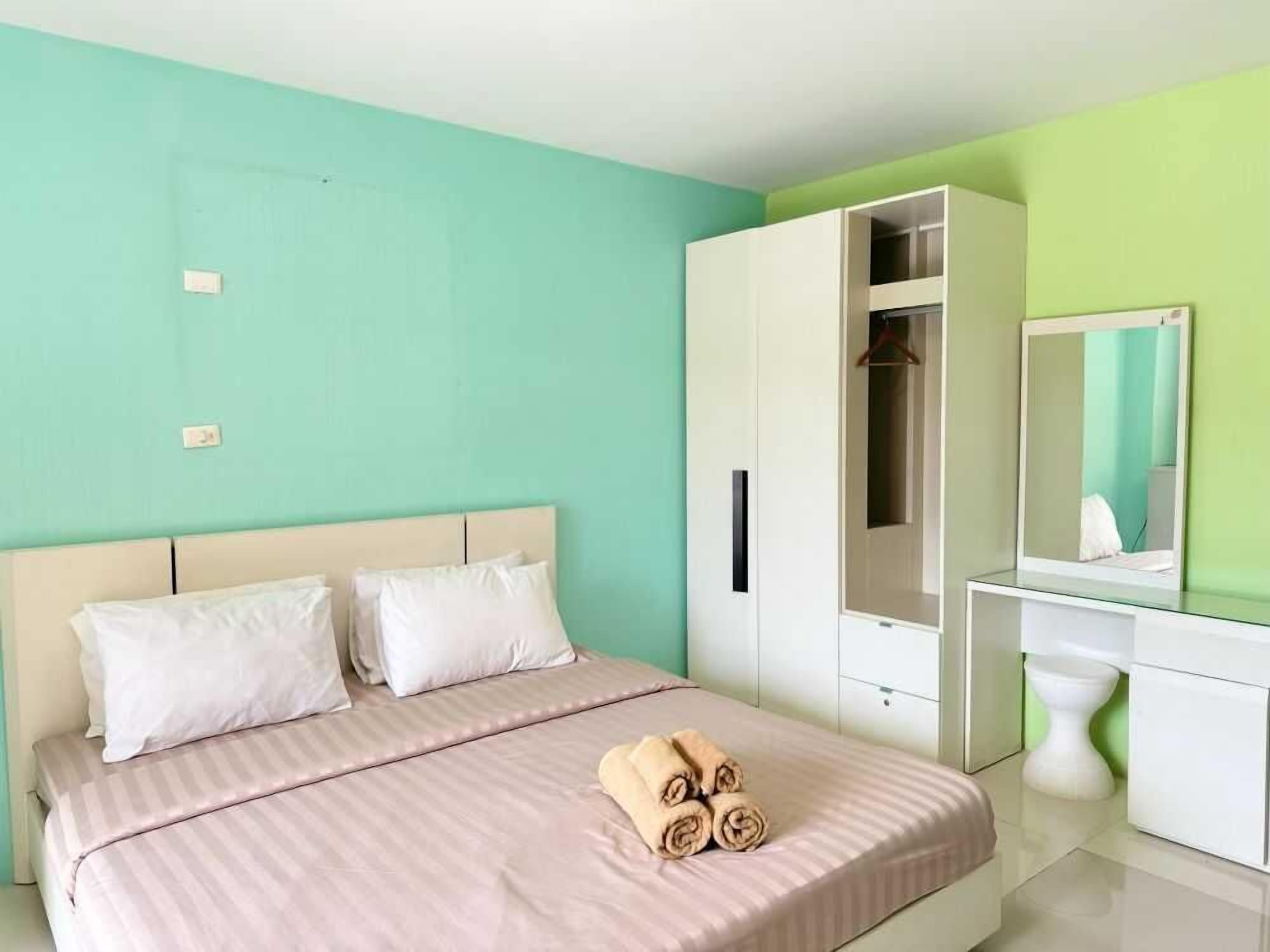 A bedroom with a bed, a wardrobe, a mirror, and a toilet.