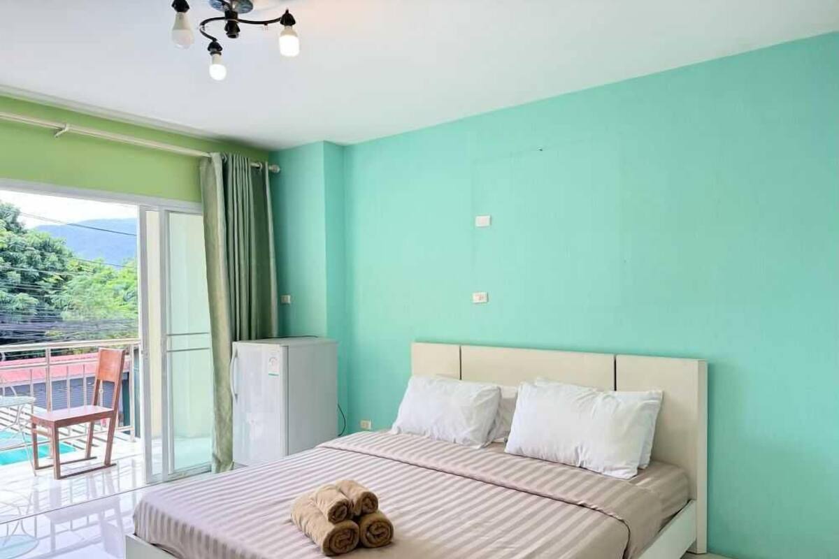 Un dormitorio con cama, un pequeño aire acondicionado y un balcón con mesa y sillas.