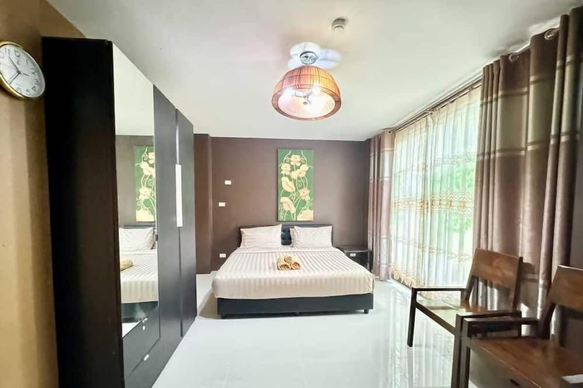 Habitación de hotel con una cama grande, un escritorio y una silla. Hay un reloj en la pared y una lámpara en el techo.
