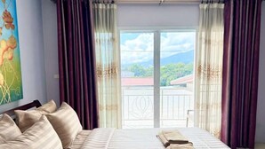 Ein Schlafzimmer mit einem großen Bett, Balkonblick und einem Bild an der Wand.
