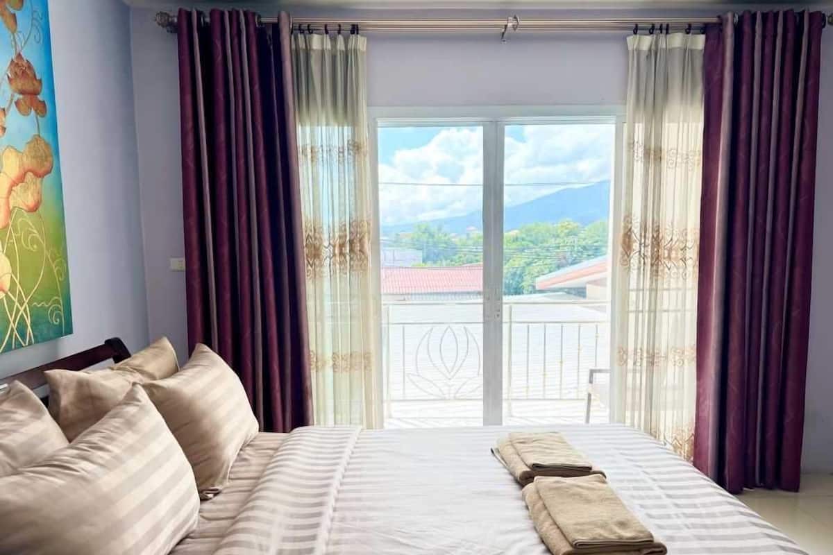 Un dormitorio con una cama grande, vistas a un balcón y un cuadro en la pared.