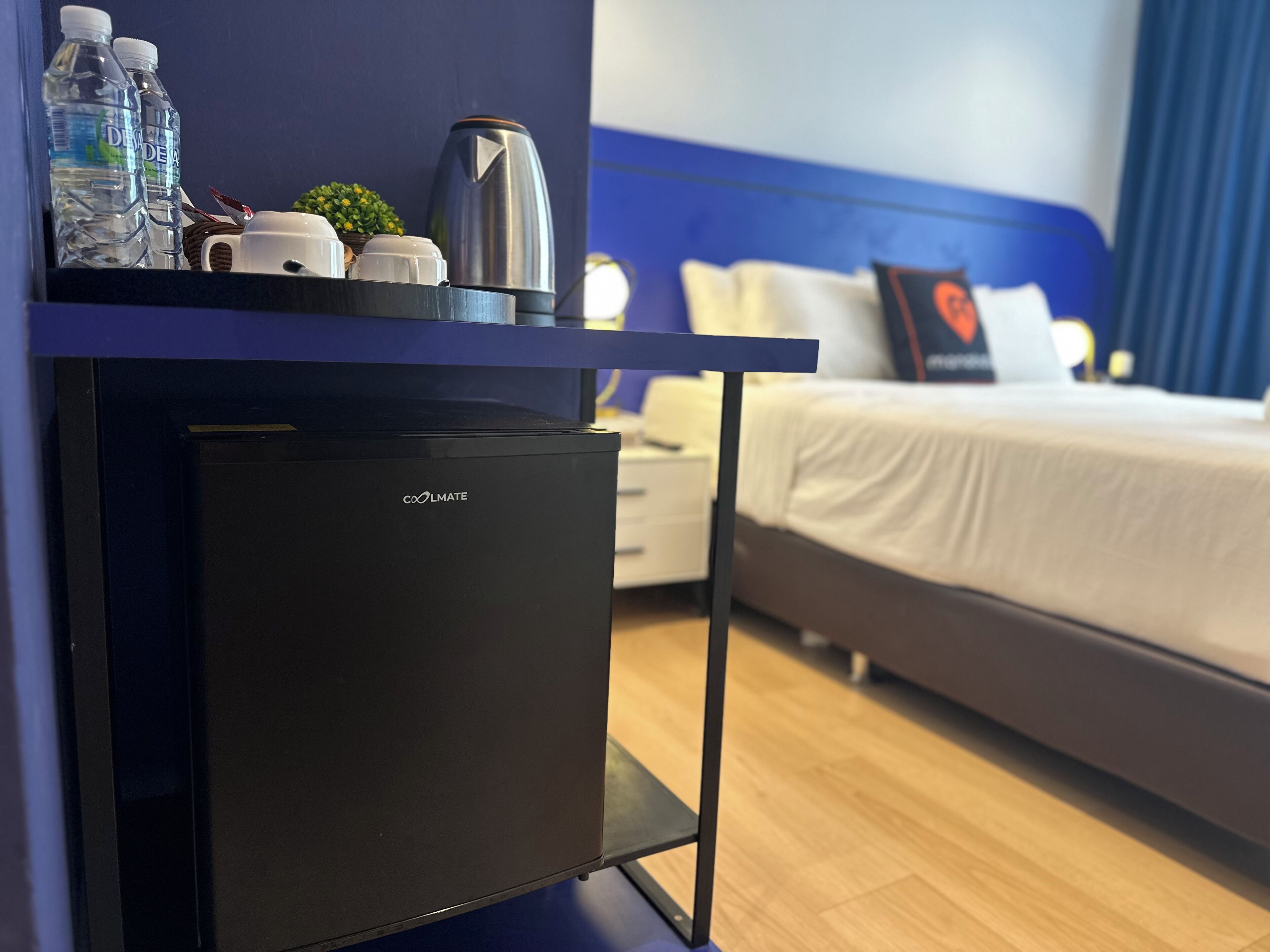 A compact minibar with a refrigerator, a kettle, and bottled water.